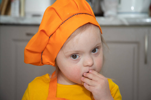 παιδί με σύνδρομο Down σεφ, ένα πορτρέτο ενός κοριτσιού με ειδικές ανάγκες. - Φωτογραφία, εικόνα