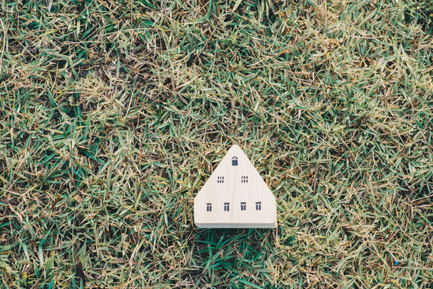 Houten speelgoed huis model op groen gras nieuwe huis business concept - Foto, afbeelding