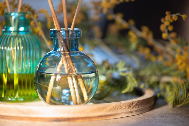 Garrafa de incenso de óleo de aroma e flores de mimosa na mesa. - Foto, Imagem
