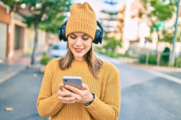 Young blonde woman using smartphone and headphones at the city. - Foto, Imagem