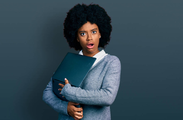 Fiatal afro-amerikai nő dolgozik számítógép laptop sokk arc, nézett szkeptikus és szarkasztikus, meglepett nyitott szájjal  - Fotó, kép