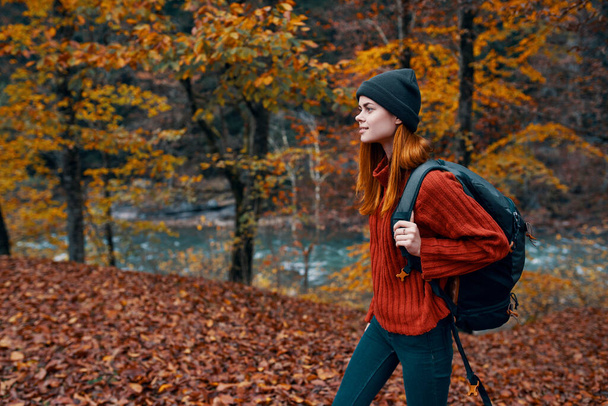 spadł liście w parku jesienią i rzeki w tle kobieta turysta z podróży plecak - Zdjęcie, obraz