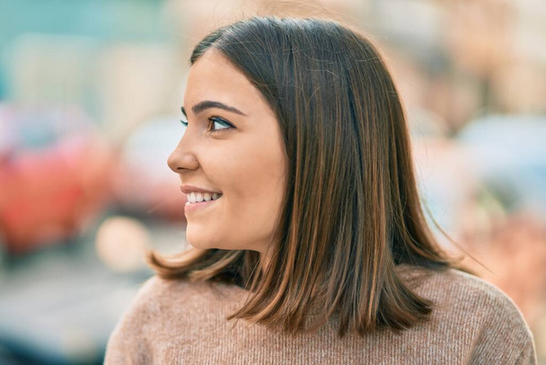 Μια νεαρή Ισπανίδα χαμογελαστή ευτυχισμένη στέκεται στην πόλη.. - Φωτογραφία, εικόνα