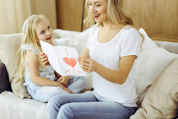 Happy mother day. Child daughter congratulates mom and gives her postcard with heart drawing. Family and childhood concepts - Φωτογραφία, εικόνα