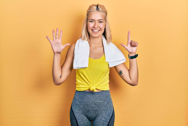 Mooie blonde sport vrouw dragen workout outfit tonen en wijzen met vingers nummer zeven terwijl glimlachen zelfverzekerd en gelukkig.  - Foto, afbeelding