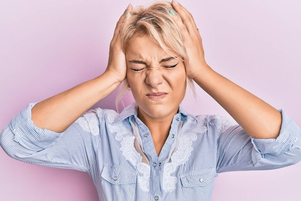 Young blonde girl wearing casual clothes suffering from headache desperate and stressed because pain and migraine. hands on head.  - Photo, Image