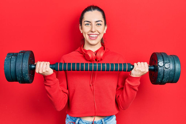 Beautiful woman with blue eyes wearing sportswear using dumbbells smiling with a happy and cool smile on face. showing teeth.  - Foto, Imagem