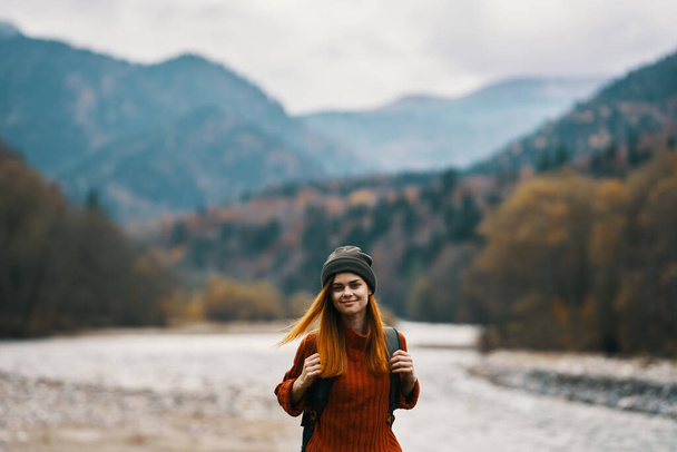 счастливая женщина в теплой одежде отдыхает в горах в осеннем пейзаже желтые листья - Фото, изображение