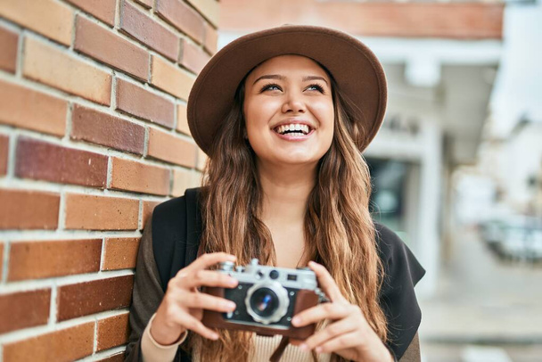 Nuori latino turisti nainen hymyilee onnellinen käyttäen vintage kamera kaupungin. - Valokuva, kuva
