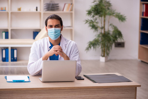 Jovem médico do sexo masculino usando máscara facial durante a pandemia - Foto, Imagem