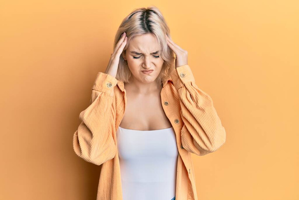 Young blonde girl wearing casual clothes with hand on head for pain in head because stress. suffering migraine.  - Foto, imagen