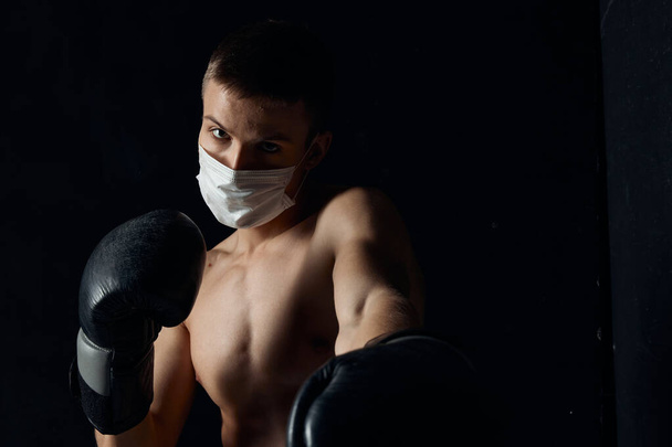 bokszoló orvosi maszkban és bokszkesztyű fekete alapon - Fotó, kép