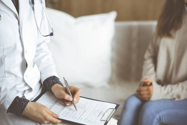 Unknown woman-doctor and patient discussing current health examination while sitting indoors. Stay at home concept during Coronavirus pandemic and self isolation quarantine - Photo, image
