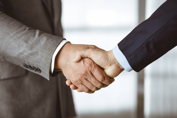 Business people in office suits standing and shaking hands, close-up. Business communication concept. Handshake and marketing - Photo, image