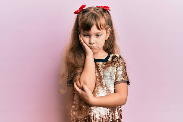 Μικρό καυκάσιο κορίτσι παιδί φορώντας εορταστικές πούλιες φόρεμα σκέψης κουρασμένος και βαρεθεί με προβλήματα κατάθλιψης με σταυρωμένα χέρια.  - Φωτογραφία, εικόνα