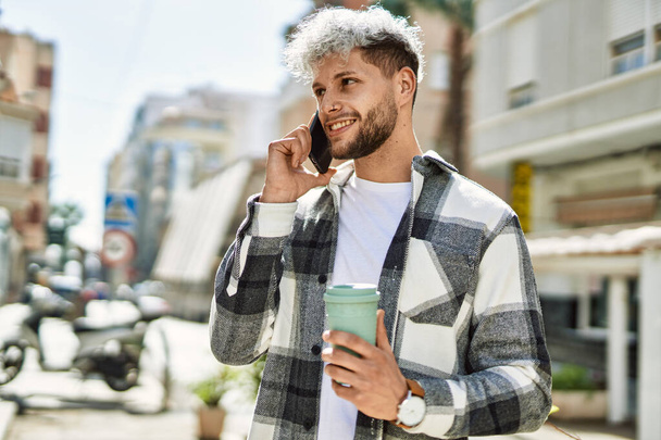 Mladý hispánec mluví smartphone pití kávy ve městě. - Fotografie, Obrázek