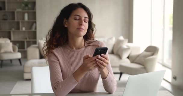 Attractive woman sit indoor holding smartphone share text messages - Felvétel, videó