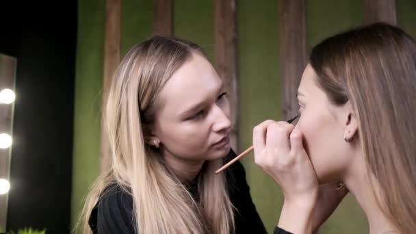 atraktivní kavkazský make-up umělec dělá make-up pro asijské ženy v salonu krásy - Záběry, video