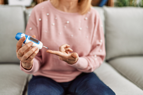 Middle age diabetic woman measuiring glucose using glucometer at home. - Φωτογραφία, εικόνα