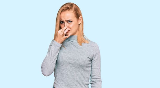 Beautiful caucasian woman wearing casual clothes smelling something stinky and disgusting, intolerable smell, holding breath with fingers on nose. bad smell  - Foto, Bild