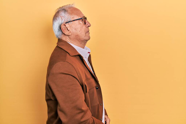 Hombre mayor con pelo gris con chaqueta casual y gafas mirando hacia un lado, pose de perfil relajado con cara natural con sonrisa confiada.  - Foto, imagen