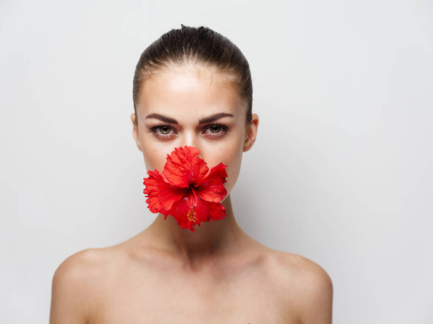 beautiful woman naked shoulders red flower cropped view light background - Fotó, kép
