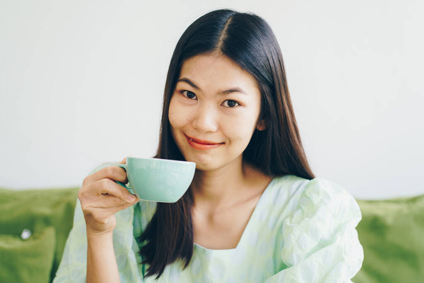 Schöne Frauen sitzen auf grünem Sofa und trinken heißen Latte-Kaffee-Aroma-Drink - Foto, Bild