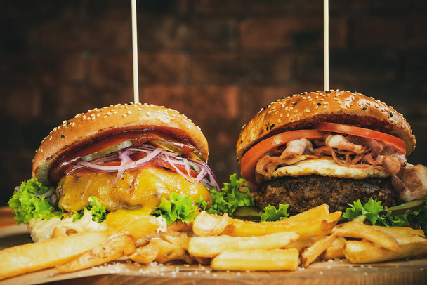 Burgers geserveerd met frietjes op houten plank. Fast Food Afhaalmaaltijden. Amerikaans restaurant. - Foto, afbeelding
