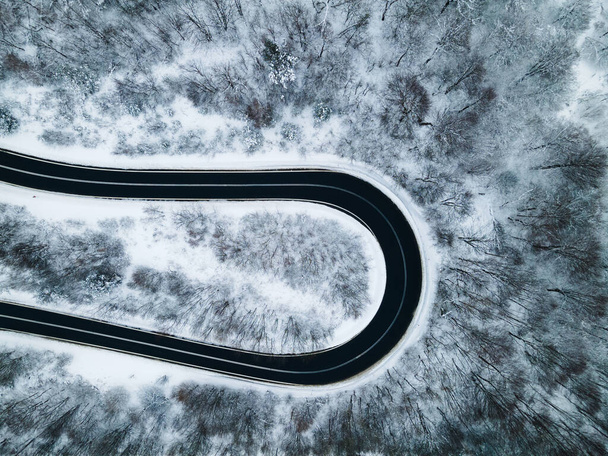 Curvy Windy Road in Snow Covered Forest, Top Down Aerial Drone View. - Photo, Image