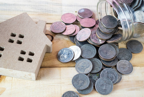 модель дома на деревянном фоне с монетами - Фото, изображение