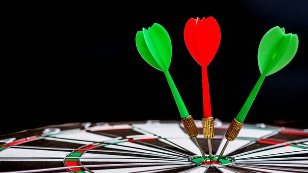 red dart arrow on center of dartboard on black background - Photo, Image