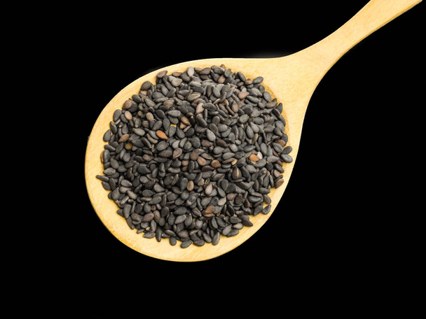 czarne nasiona sezamu w drewnianej łyżce na ciemnym tle - Zdjęcie, obraz