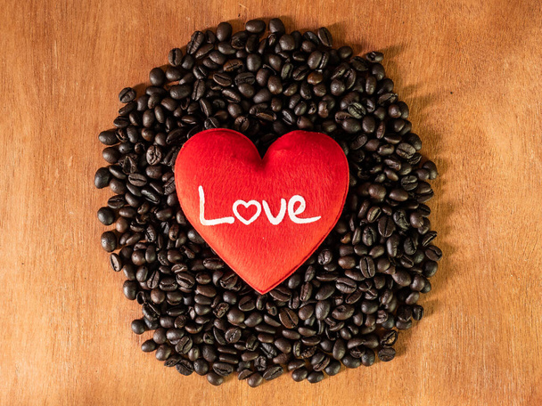 красное сердце на кофейных бобах на деревянном копировальном пространстве - Фото, изображение