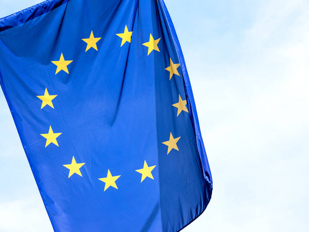 Euroopan unionin lippu, EU-tunnus lähellä, 12 tähden lippu esine yksityiskohta, lähikuva, kirkas taivas taustalla, kukaan. Politiikka, talous, liiketoiminta ja EU, Eurooppa kulttuuri, lait abstrakti käsite - Valokuva, kuva
