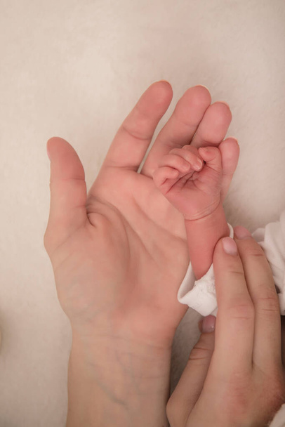 La mano paterna sostiene una palma del bebé. Concepto de amor y familia. Las manos de la madre y el bebé de cerca imagen. - Foto, imagen