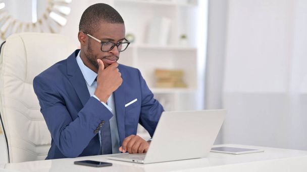 Pensive African Businessman myślenie i praca na laptopie  - Zdjęcie, obraz