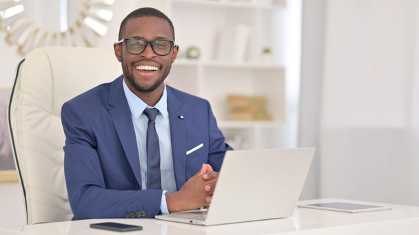 Nuori afrikkalainen liikemies kannettavan tietokoneen kanssa hymyilee kameralle  - Valokuva, kuva