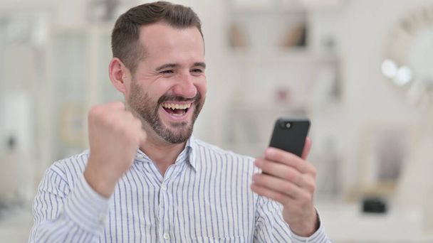 Portrait of Excited Young Man Celebrating on Smartphone  - Φωτογραφία, εικόνα