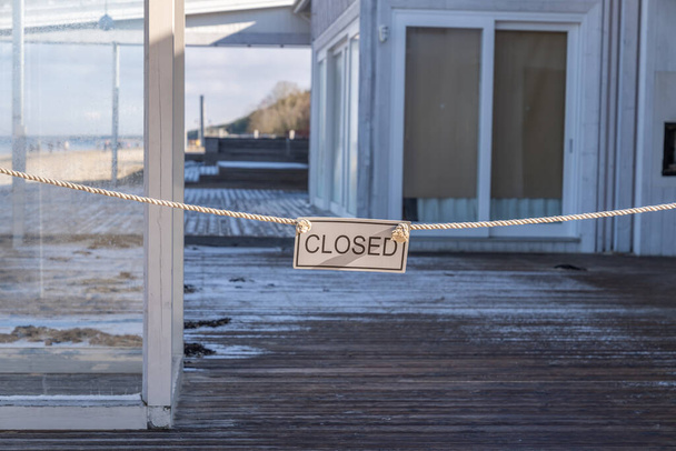 Panneau fermé accroché à l'entrée d'une terrasse vide d'un restaurant de plage - Photo, image