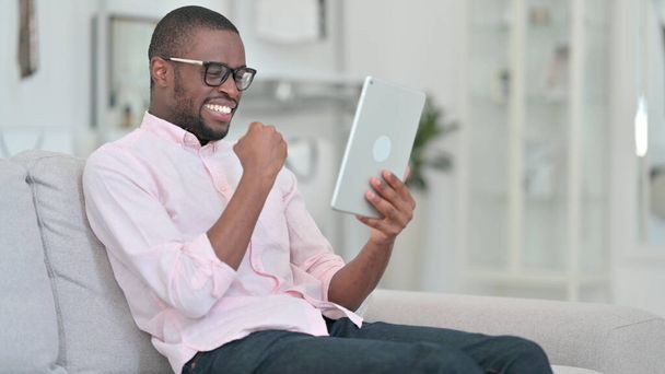 Homme africain excité célébrant le succès sur tablette à la maison  - Photo, image