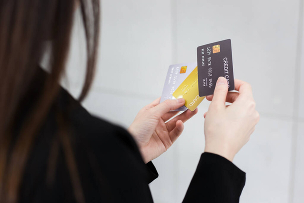 Жінка в чорному формальному костюмі тримає кредитні картки в руках. Вона вибирала кредитні картки, щоб використовувати їх у фінансовій концепції
. - Фото, зображення