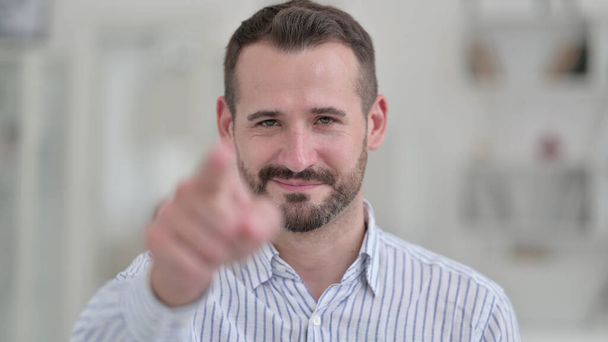 Porträt eines jungen Mannes, der mit dem Finger auf die Kamera zeigt  - Foto, Bild
