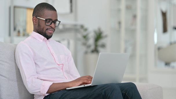 Hardwerkende jonge Afrikaanse man Werken op laptop thuis  - Foto, afbeelding