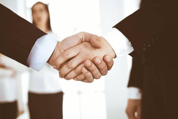 Businessman and woman shaking hands in office. Concept of handshake as success symbol in business - Photo, image