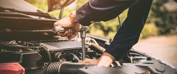 Mãos de close-up do mecânico de automóveis estão usando a chave para reparar e manutenção do motor automático é problemas na oficina de reparação de automóveis. Conceitos de verificação de assistência automóvel e seguro fixo e de serviços. - Foto, Imagem