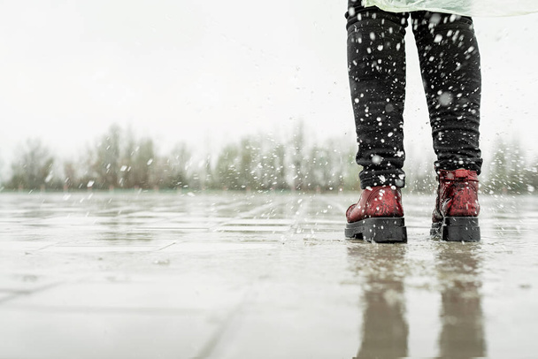 woman running on asphalt in rainy weather. Close up of legs and shoes splashing in puddles. - Photo, Image