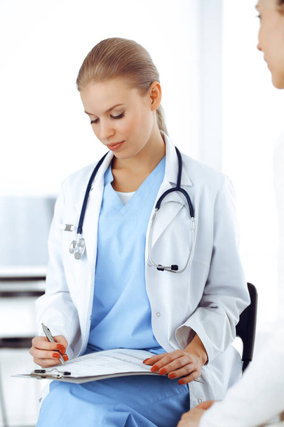 Kobieta - lekarz konsultuje się z pacjentką podczas korzystania z notatnika i historii leczenia. Koncepcja medycyny - Zdjęcie, obraz