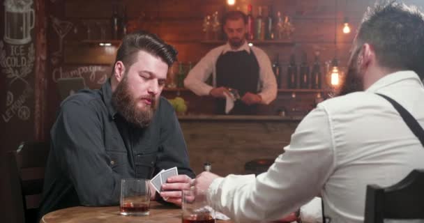 Zwei Männer beenden ein Kartenspiel und schütteln lächelnd Hände - Filmmaterial, Video