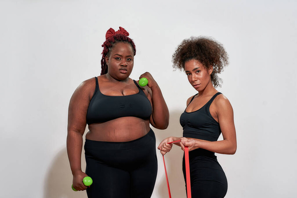 Picture of two afro women holding dumbbells and skipping rope, each and every body in this world is beautiful - Photo, image