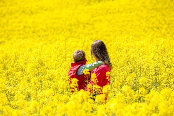 Madre e hijo paseando por los campos de colza - Foto, immagini